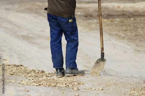 Принти на полотні A worker with a shovel strews gravel in pits to level the road