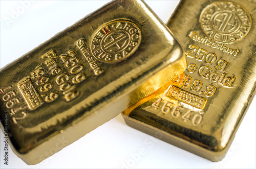 Two cast gold bars on a white background. Selective focus.