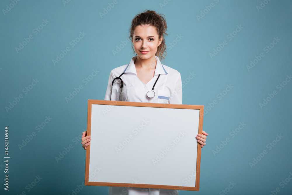 Smiling female doctor showing blank board Smiling female doctor showing blank board