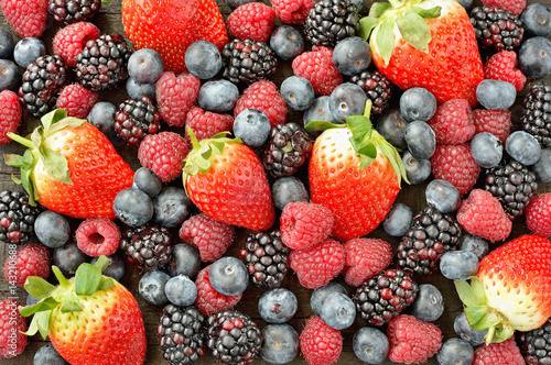 Fototapeta Naklejka Na Ścianę i Meble -  Mix of strawberries, blackberries, blueberries and raspberries on wood table. Healthy forest fruit. Delicious fresh berries background.