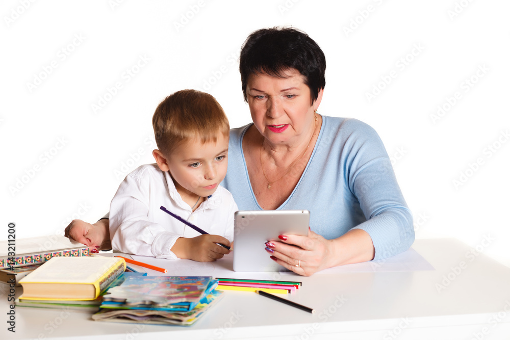 Grandmother with grandson learn and draw at table on a white background Grandmother with grandson learn and draw at table on a white background