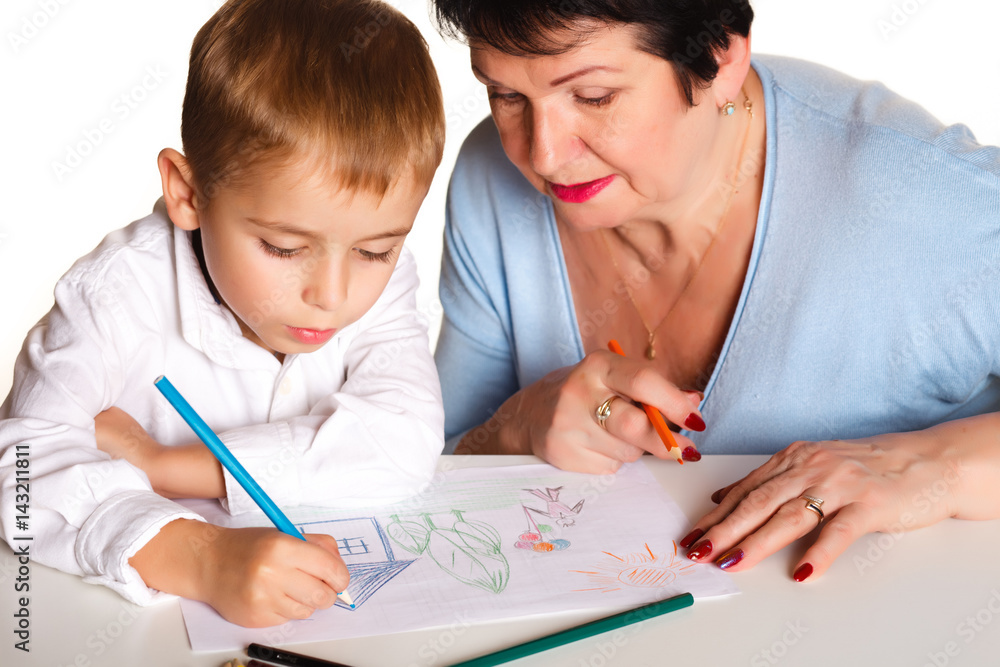 Grandmother with grandson learn and draw at table on a white background Grandmother with grandson learn and draw at table on a white background