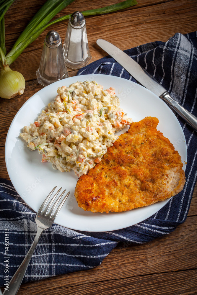 Fried pork chop in breadcrumbs, served with vegetable salad. Fried pork chop in breadcrumbs, served with vegetable salad.