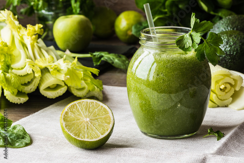 Detox diet. Green smoothie with different vegetables on wooden background photo