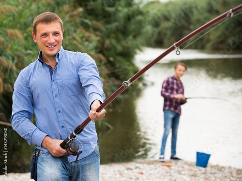 Excited adult man fishing on freshwater lake