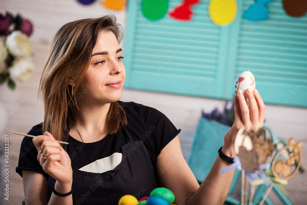 Fototapeta premium colouring eggs for eastertime at home.Happy easter! A mother,girl painting Easter eggs. Happy family preparing for Easter.decorating Easter eggs, woman hands hold a paintbrush and paint