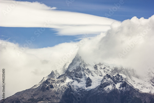 mountains of patagonia in haze at daylight with windy lenticular clouds