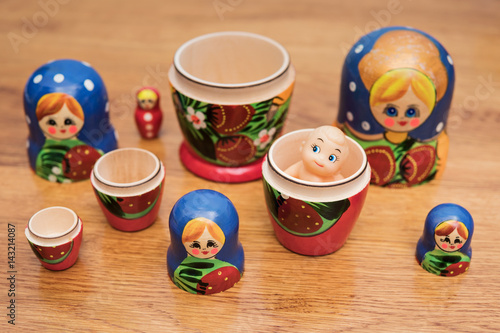 Many open Russian nested dolls on a wooden table with a little doll in one of them
