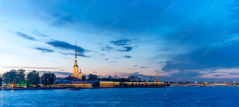 Obraz premium Peter and Paul fortress with the Palace promenade at sunset on a background of pure pink sky with reflection in the water of the Neva river during the white nights in St. Petersburg