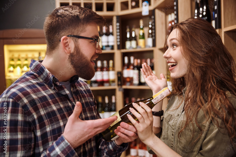 Side view of Surprised couple choosing bottle of wine