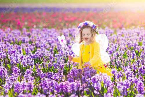 Little girl in fairy costume playing in flower field