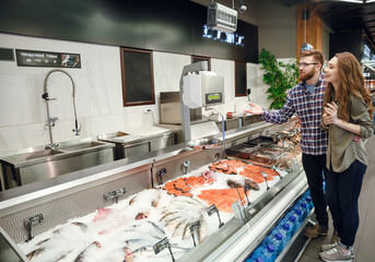 Full length portrait of couple choosing fish
