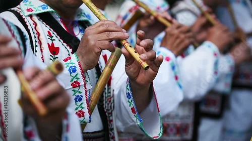 People in romanian traditional costumes singing at wooden flutes photo