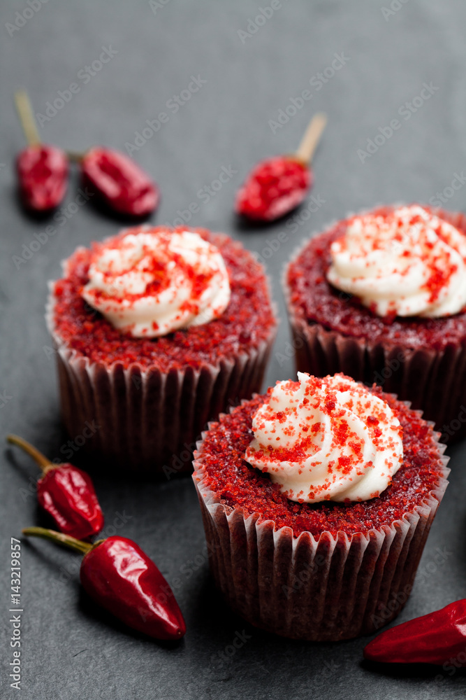Chocolate cupcakes with red hot chili pepper on black stone background Chocolate cupcakes with red hot chili pepper on black stone background