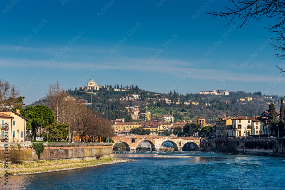 Verona, Italy - MARCH, 2017: Ancient bridge on Adige-river Ponte Pietra in Verona and Verona Santuario della Madonna di Lourdes, Italy