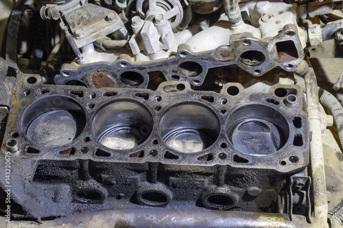 The cylinder block of the four-cylinder engine. Disassembled motor vehicle for repair. Parts in engine oil. Car engine repair in the service