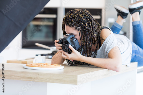 Girl lying on table and photographing cake