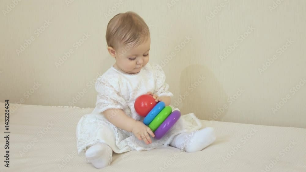 Little smiling girl in a white dress playing in a pyramid Little smiling girl in a white dress playing in a pyramid