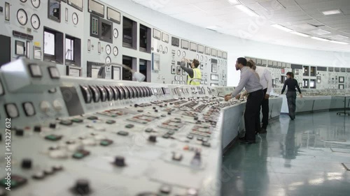  Workers in power plant control room, pressing switches on control desk photo