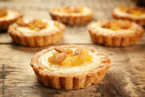 Delicious crispy tarts with almond and raisins on wooden table
