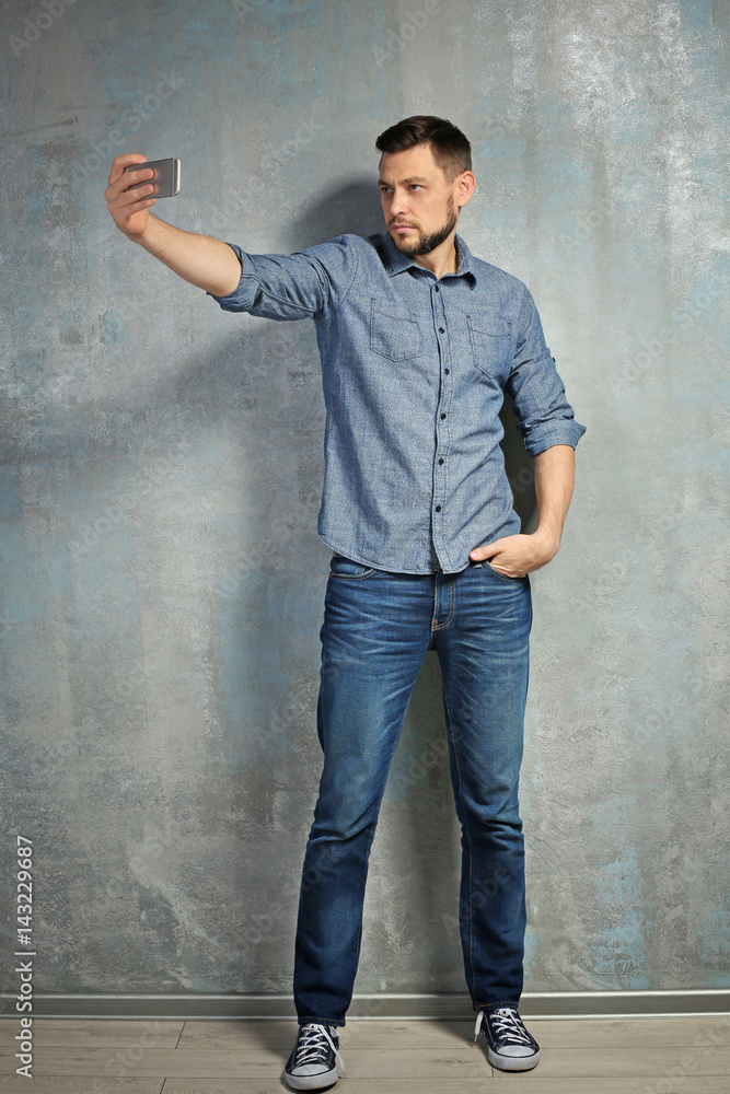 Young man taking selfie while standing near textured wall Young man taking selfie while standing near textured wall
