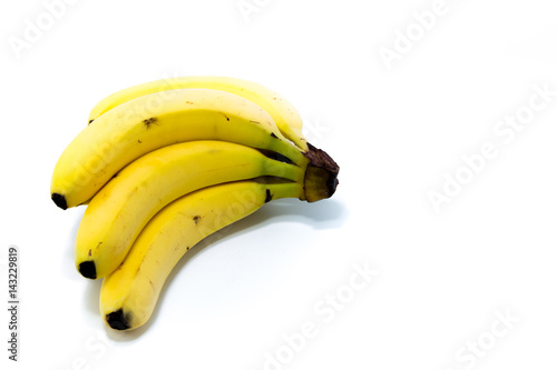 Four fresh golden bananas with two strawberries isolated in white background