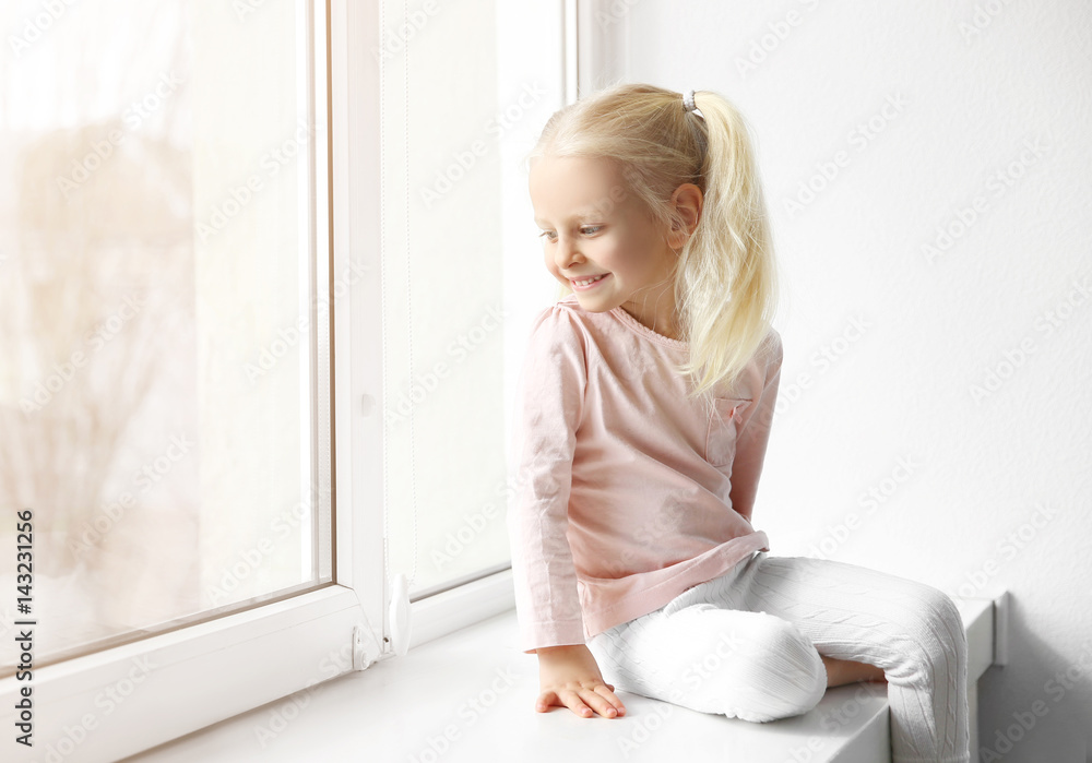 Cute little girl sitting on windowsill Stock Photo | Adobe Stock