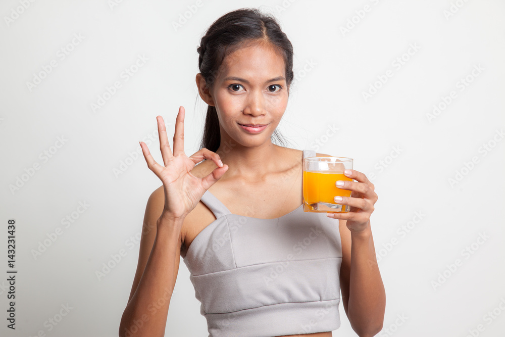 Young Asian woman drink orange juice show OK sign. Young Asian woman drink orange juice show OK sign.
