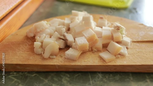 Cutting pork fat with a knife on a cutting board