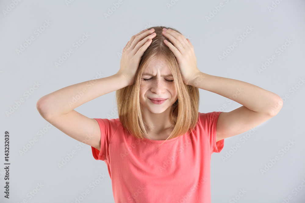 Cute girl suffering from headache on light background Cute girl suffering from headache on light background