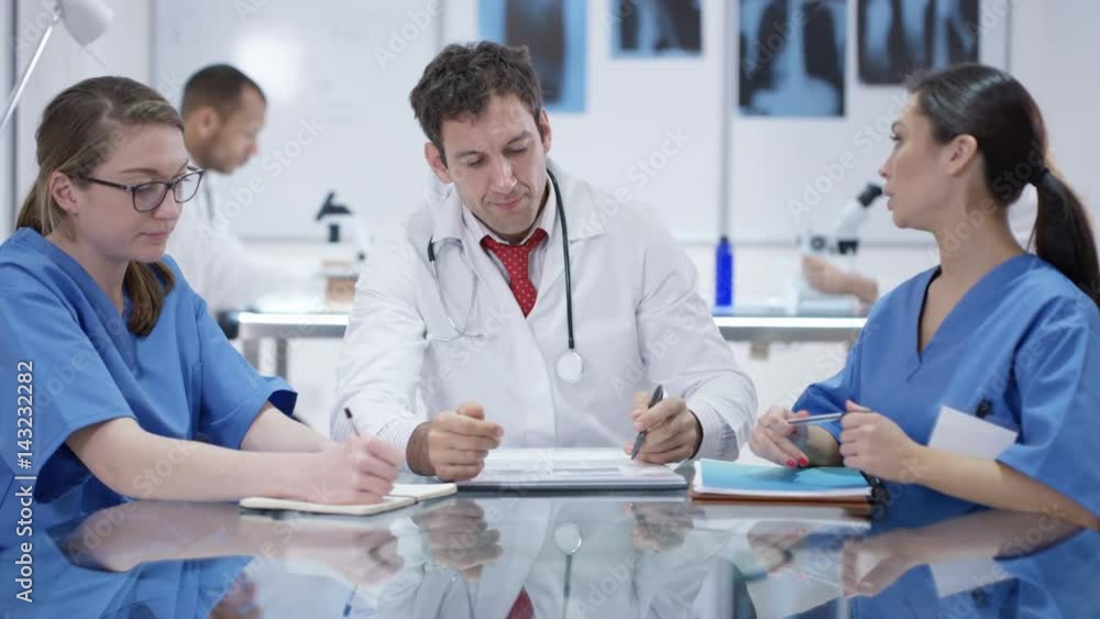 Medical team in a meeting with colleagues working in background Medical team in a meeting with colleagues working in background