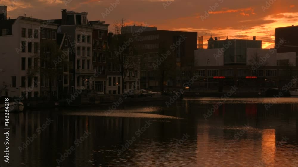 A wide establishing shot showing the Amstel river and the National Opera House in Amsterdam, The Netherlands, during sunrise
A wide establishing shot showing the Amstel river and the National Opera House in Amsterdam, The Netherlands, during sunrise