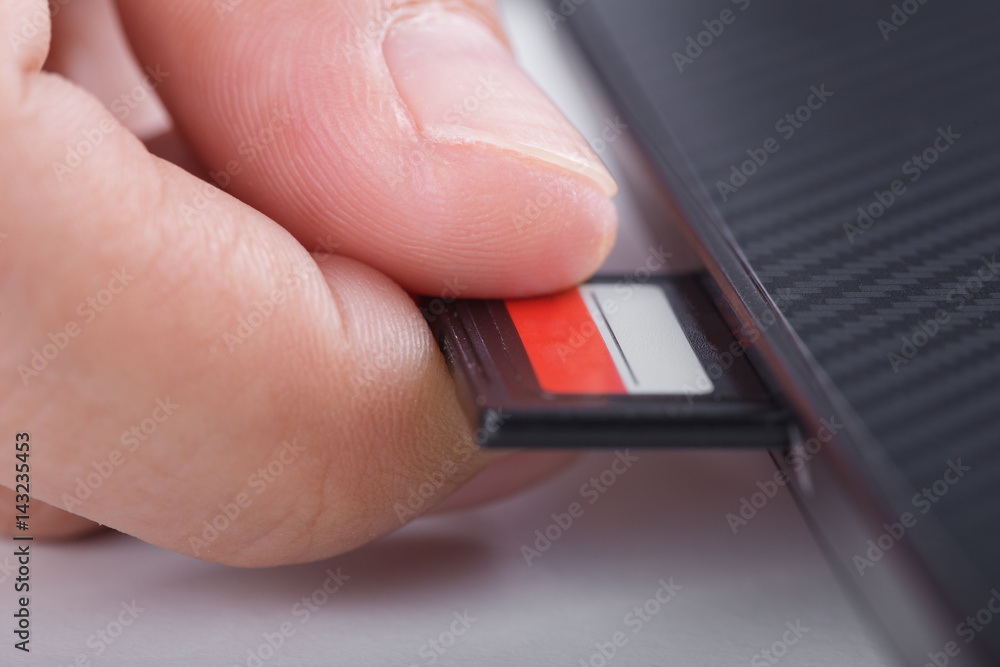 hand inserting SD card into laptop Stock Photo Adobe Stock