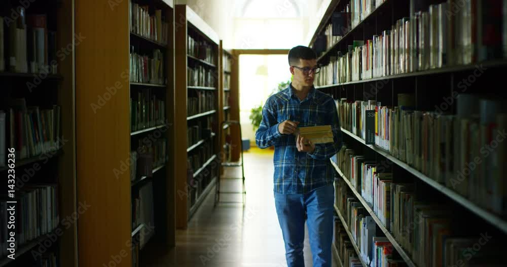 A beautiful young boy studying in a happy and carefree library reading the book. Concept: educational, portrait, library, and studious, relax. A beautiful young boy studying in a happy and carefree library reading the book. Concept: educational, portrait, library, and studious, relax.