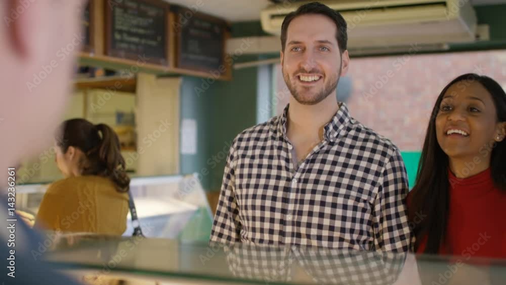 Couple in a bakery shop being served at the counter Couple in a bakery shop being served at the counter