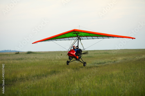 Hang glider takes off from the grassy field.