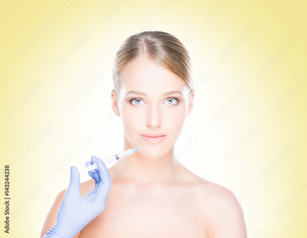 Young, beautiful and healthy woman having skin injections over yellow background. Plastic surgery concept.