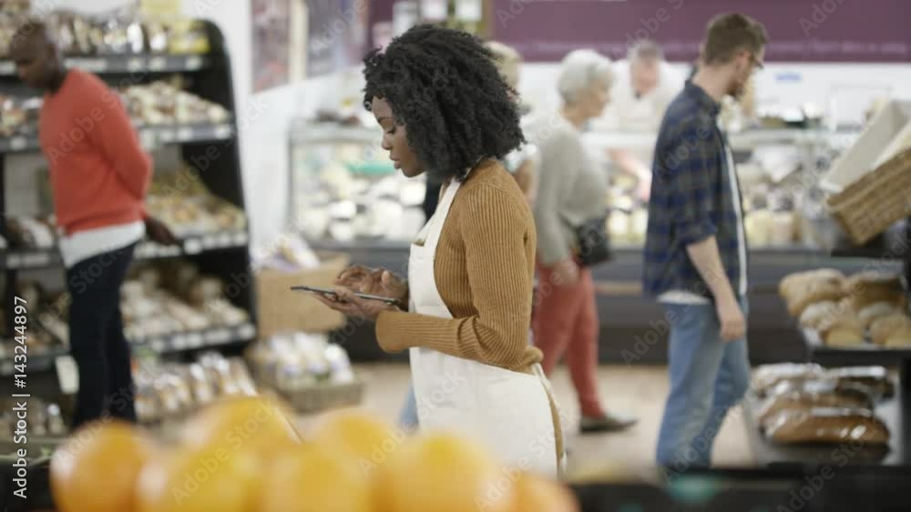Worker in a supermarket looking at tablet computer & checking stock Worker in a supermarket looking at tablet computer & checking stock