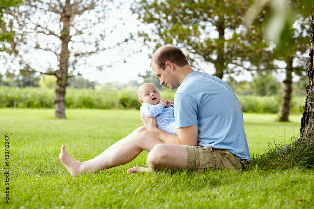 Fototapeta premium Smiling young man looking at his newborn son