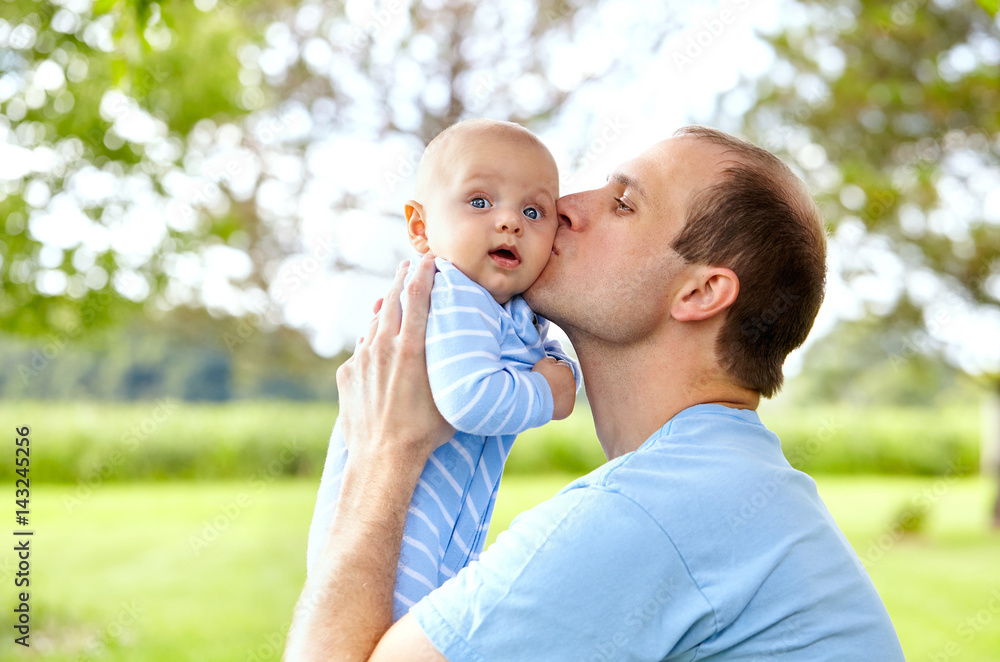 Portrait of young father kissing his newborn son Portrait of young father kissing his newborn son