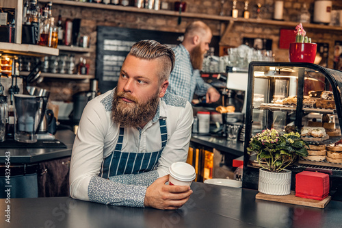 Bearded barista male at bar stand in a coffee shop.