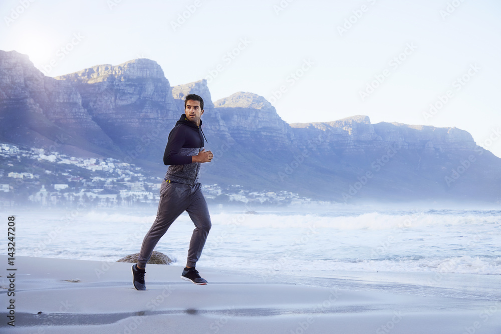 Jogging dude on beach, looking away