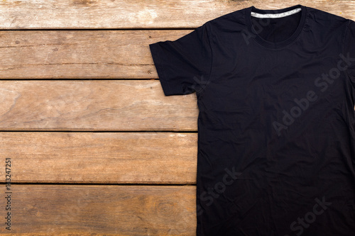 Black color t-shirt mock-up on wooden background. unfold single shirt round neck(O-neck)