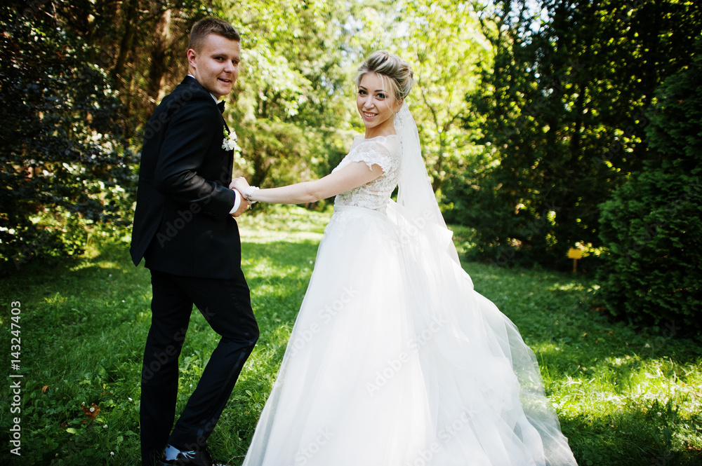 Stylish and gorgeous wedding couple walking outdoor at park on sunny weather.