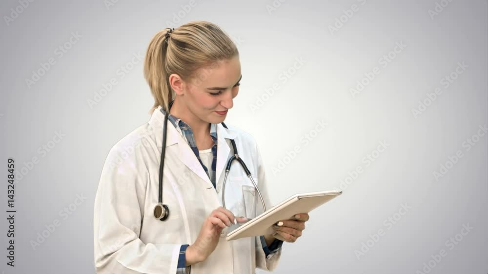 Charming female doctor with stethoscope smiling while using tablet computer on white background. Charming female doctor with stethoscope smiling while using tablet computer on white background.