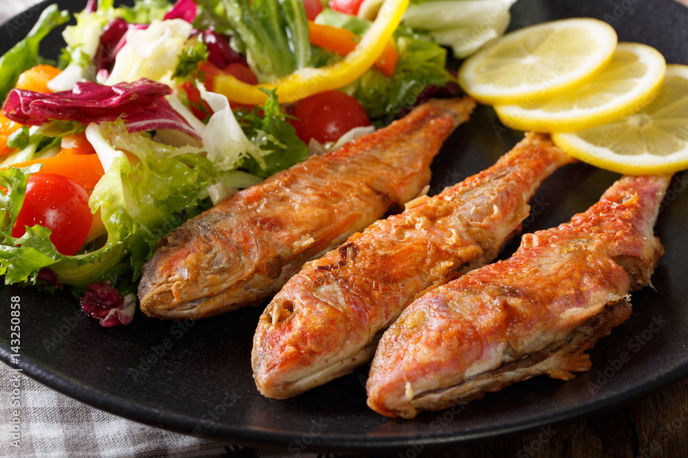 Fried red mullet with fresh vegetable salad and lemon close-up. horizontal Fried red mullet with fresh vegetable salad and lemon close-up. horizontal