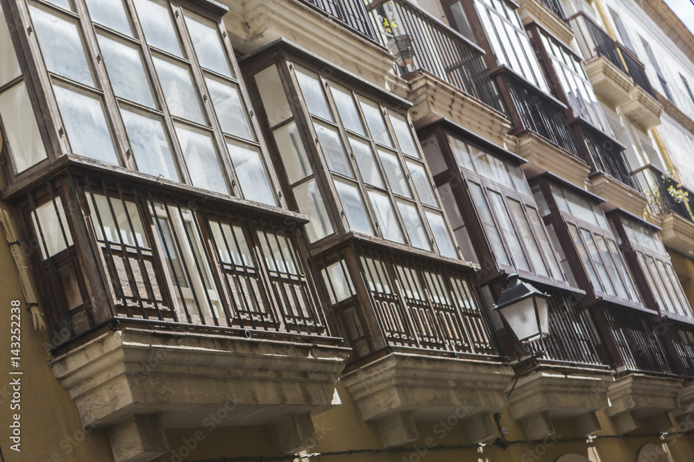 Obraz premium Detail of balconies and large windows on the time of the nineteenth century, Narrow street with traditional architecture in Cadiz, Andalusia, southern Spain