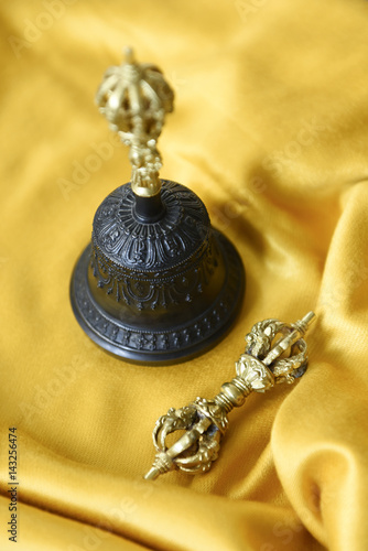 Small metal scepter called dorje or vajra and Tibetan prayer bell for meditation photo