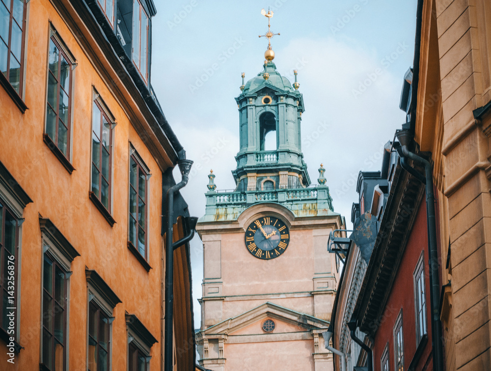 View of the Cathedral of Saint Nicholas Sankt Nikolai kyrka or Storkyrkan Bell Tower beetwen houses in Stockholm, Sweden.