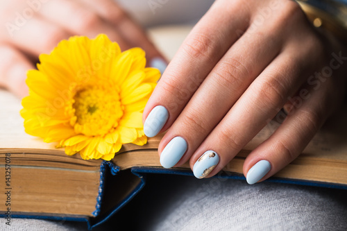 Girl's hands on a book with a yellow flower